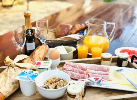 Uitgebreid ontbijt op de houten tafel onder de pergola